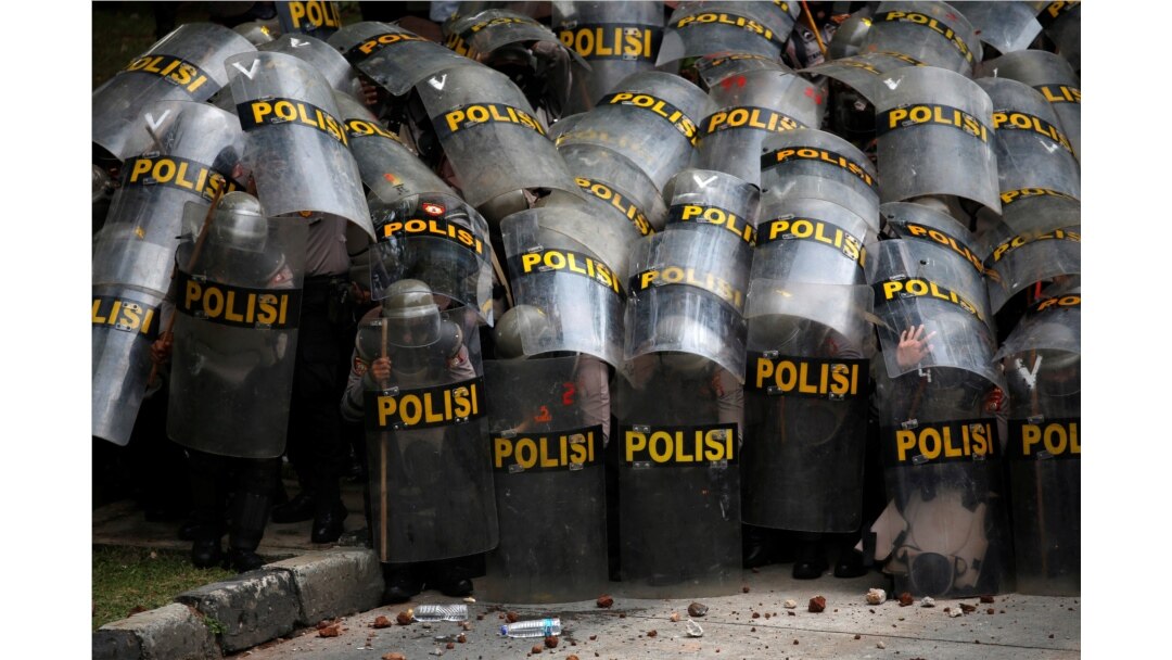 Police officers protect themselves with their shields during a protest against the new Job Creation Law, in Jakarta, Indonesia, Oct. 13, 2020.