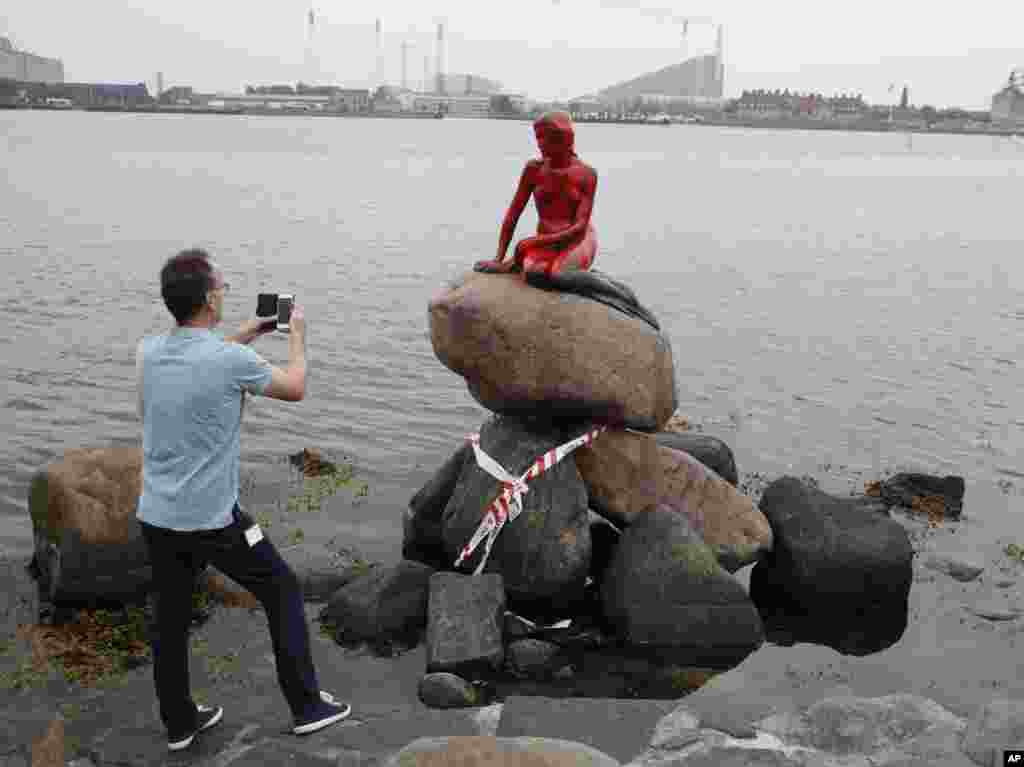 A man photographs the vandalized tourist attraction "The Little Mermaid" in Copenhagen, Denmark.