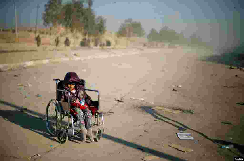 A disabled Iraqi girl who fled her home waits in the street for a truck to take her to a safe place, as Iraqi forces battle with Islamic State militants, in western Mosul.