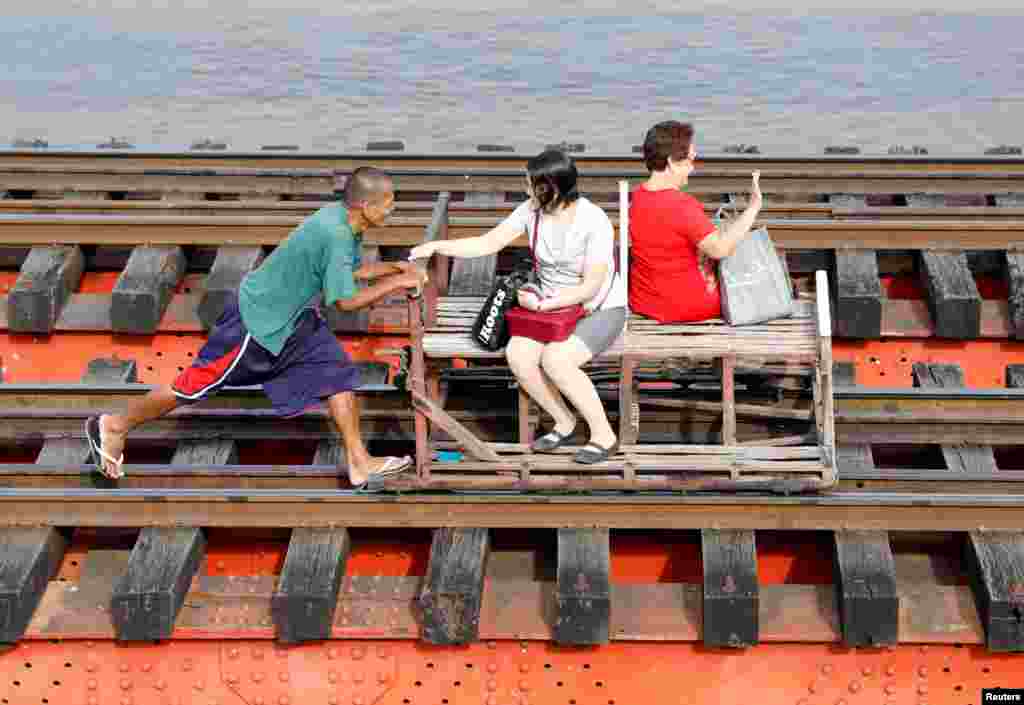 A man pushes a trolley along a railroad to transport commuters in Manila, the Philippines, Feb. 21, 2017.