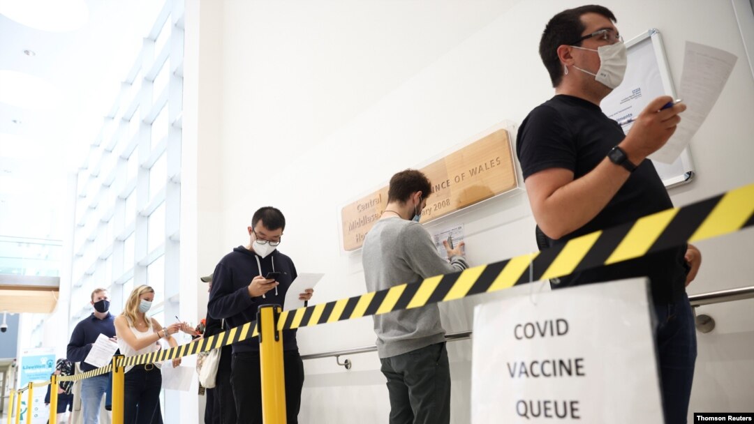 People queue to receive a dose of the Pfizer BioNTech vaccine at the Central Middlesex Hospital in London, Aug. 1, 2021.