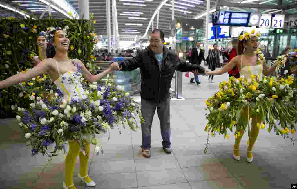Models in Utrecht, Netherlands, wear floral arrangements as they interact with travelers to promote Keukenhof, the largest flower show in the world.