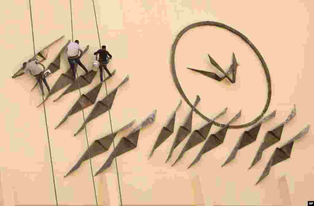 Workers clean a moral at the Art Creation Center at the opera house in Cairo, Egypt.