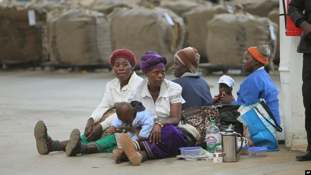 FILE - Indigenous tobacco farmers, with their children, wait to sell their tobacco, at Boka Tobacco auction floors, in Harare, Zimbabwe, May 14, 2013. 