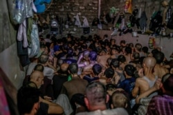 FILE - In this July 18, 2017 file photo, suspected Islamic State members sit inside a small room in a prison south of Mosul, Iraq. In some cells in Iraq, Iran, Syria and other countries in the Middle…