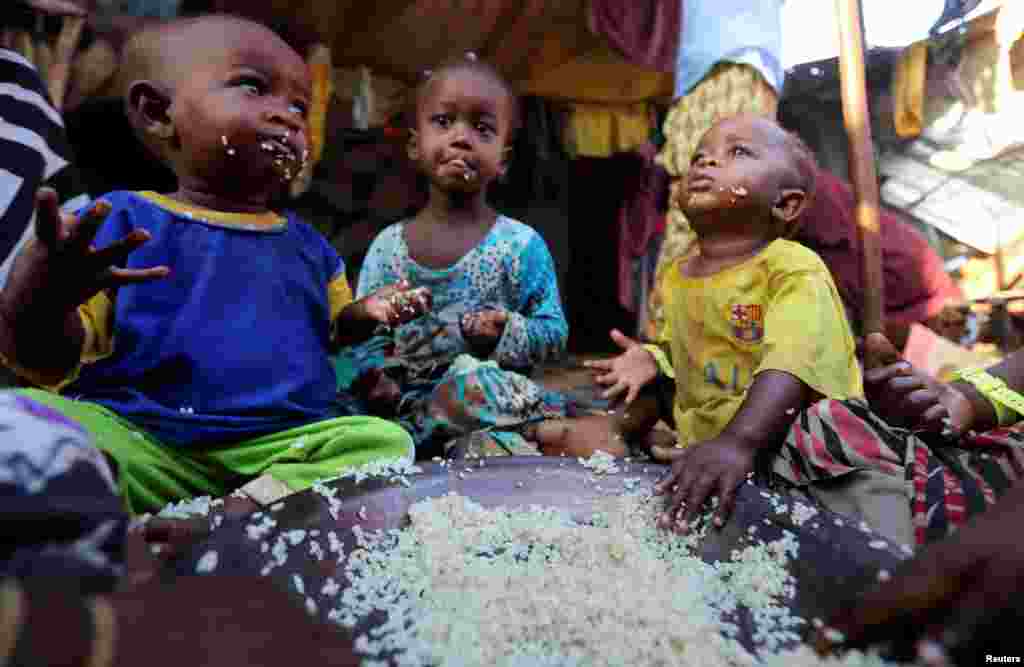 Internally displaced Somali children eat boiled rice outside their family's makeshift shelter at the Al-cadaala camp in Mogadishu.