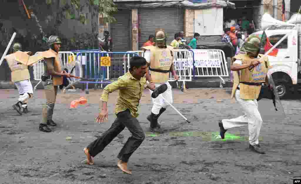 An activist of the Bhartiya Janata Party (BJP) runs past Indian police in Kolkata during a protest over alleged police abuses against their fellow BJP workers.