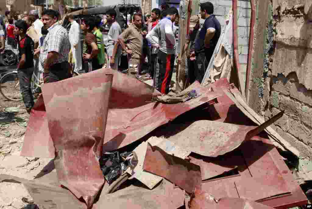 Civilians gather at the scene of a car bomb attack in east Baghdad, April 15, 2013. 