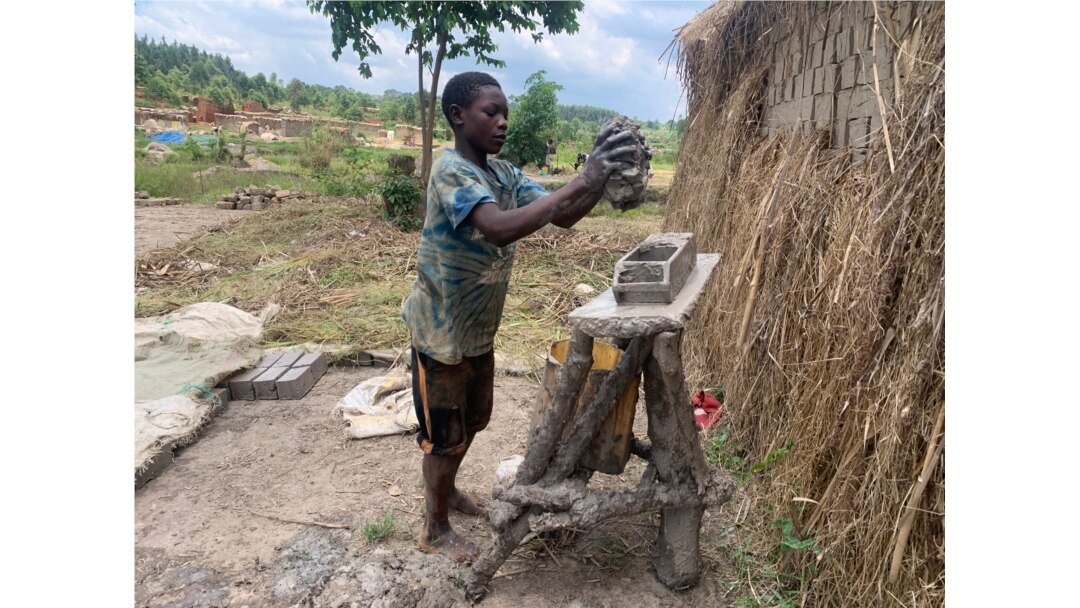 Fourteen-year-old Musa Ssewanyana, a high school student, drops a mold of clay sand preparing to lay bricks in Ntawo village, Mukono district, Uganda, Aug. 1, 2020. (Halima Athumani/VOA)