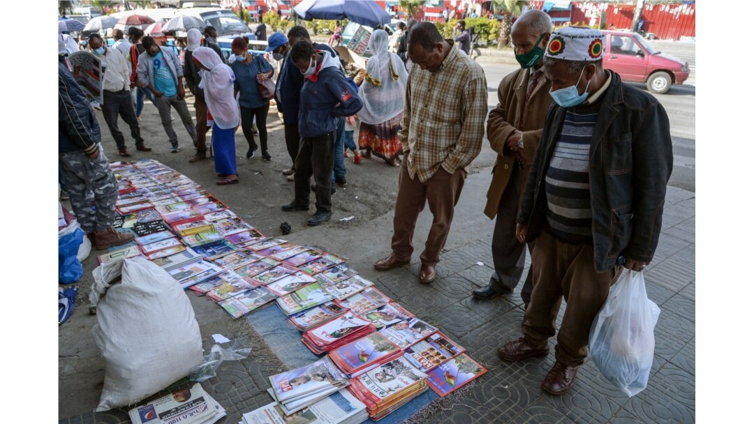 Ethiopians check newspapers and magazines reporting on the current military confrontation in Ethiopia's Tigray region, at a news stand on a street in the capital Addis Ababa, Nov. 7, 2020.