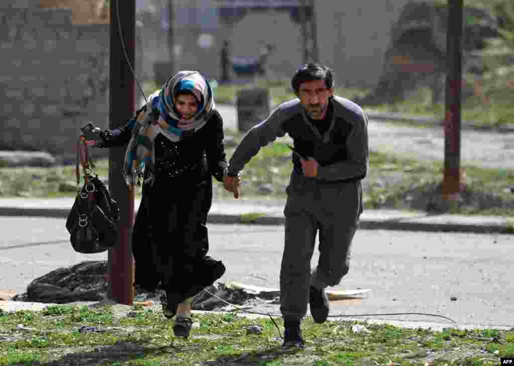 Iraqis run for cover as they flee Mosul's Al-Tayaran neighborhood during an offensive by Iraqi forces to retake the area from Islamic State (IS) group fighters.