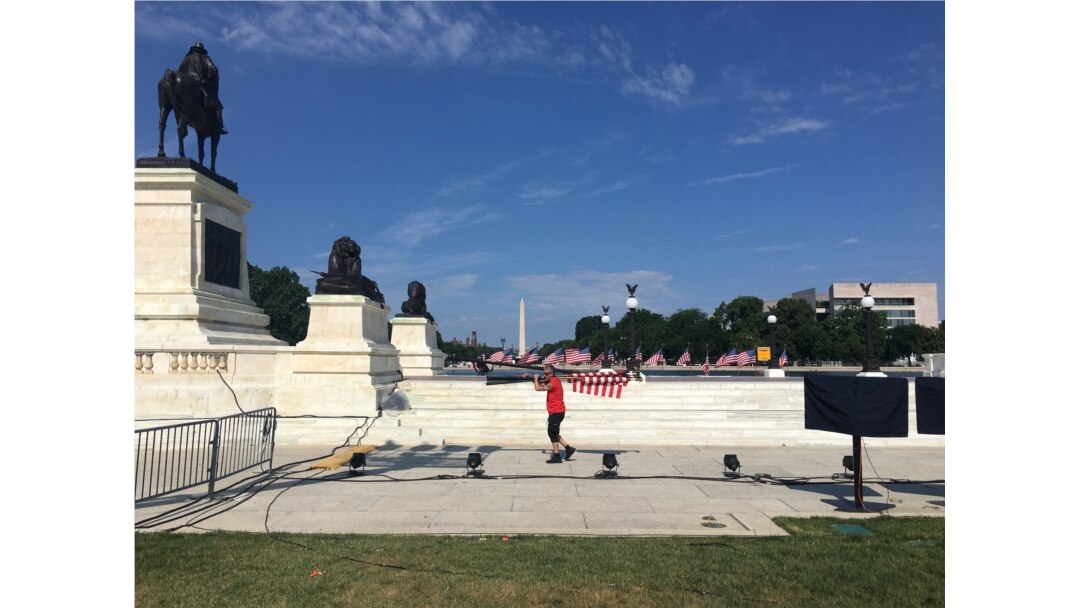 A man caries a bunch of U.S. flags outside the Capitol as preparations for Independence Day Celebrations continue in Washington, DC, July 3, 2019. (Photo by Diaa Bekheet)