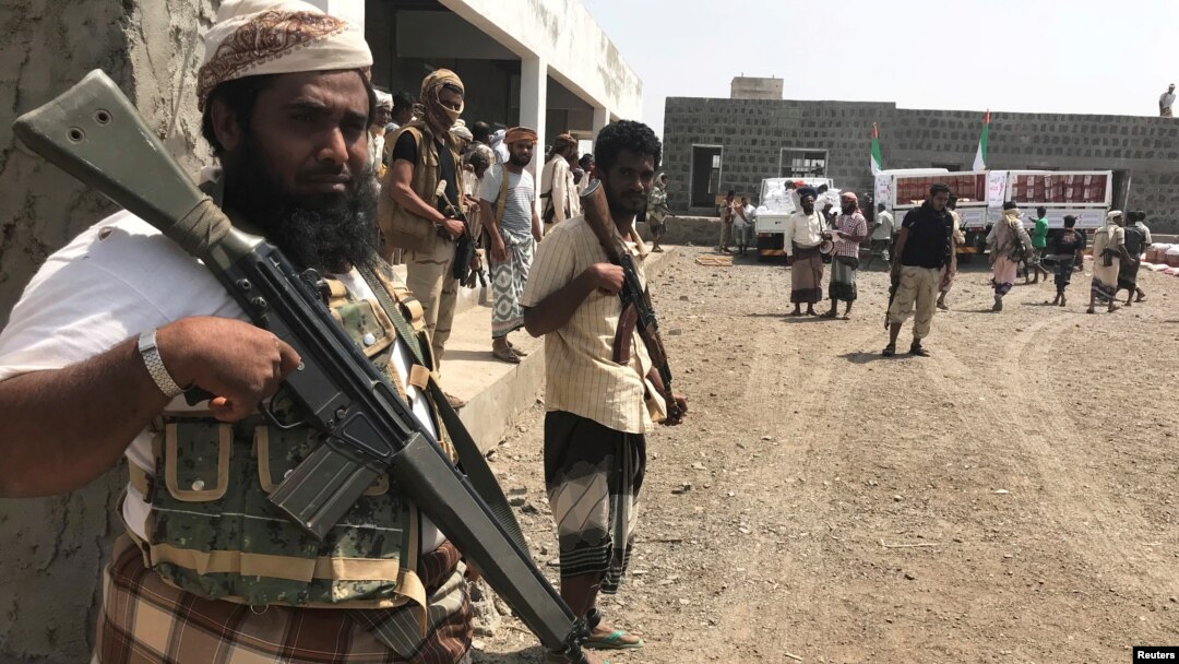 FILE - Yemeni fighters secure a building where UAE Red Crescent distribute aid to displaced people in Al-Mokha, Yemen, March 6, 2018. 