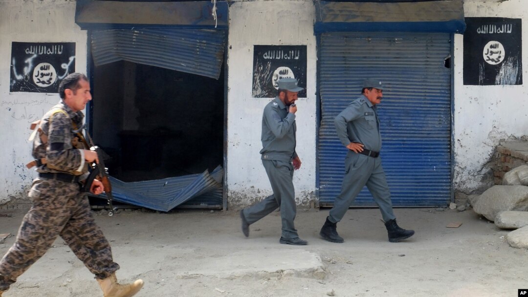 FILE - Afghan police walk past Islamic State militant flags on a wall, after an operation in the Kot district of Jalalabad province east of Kabul, Aug. 1, 2016. China, Pakistan and Russia will meet in Moscow, Dec. 27. 2016, to review "gradual growing" threat of Islamic State from spreading beyond Afghanistan.