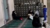 Syrian women rest at the entrance of a mosque in the neighborhood of Basmane, which is filled with transient migrants on their way to Europe, in the Aegean port city of Izmir, western Turkey, March 8, 2016. 