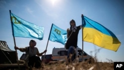 Місцеві жителі тримають українські та кримськотатарські прапори в селі Чонгар, Україна, 20 вересня 2015 р. AP Photo/Євген Малолєтка