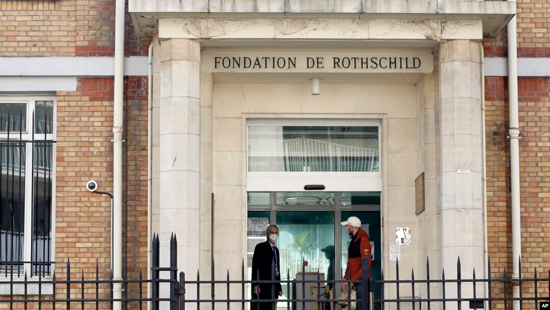 Men wearing face masks at the entrance of the Fondation Rothschild nursing home, in Paris, March 27, 2020. Governments in Europe's hardest-hit countries have yet to systematically test the residents of nursing homes.