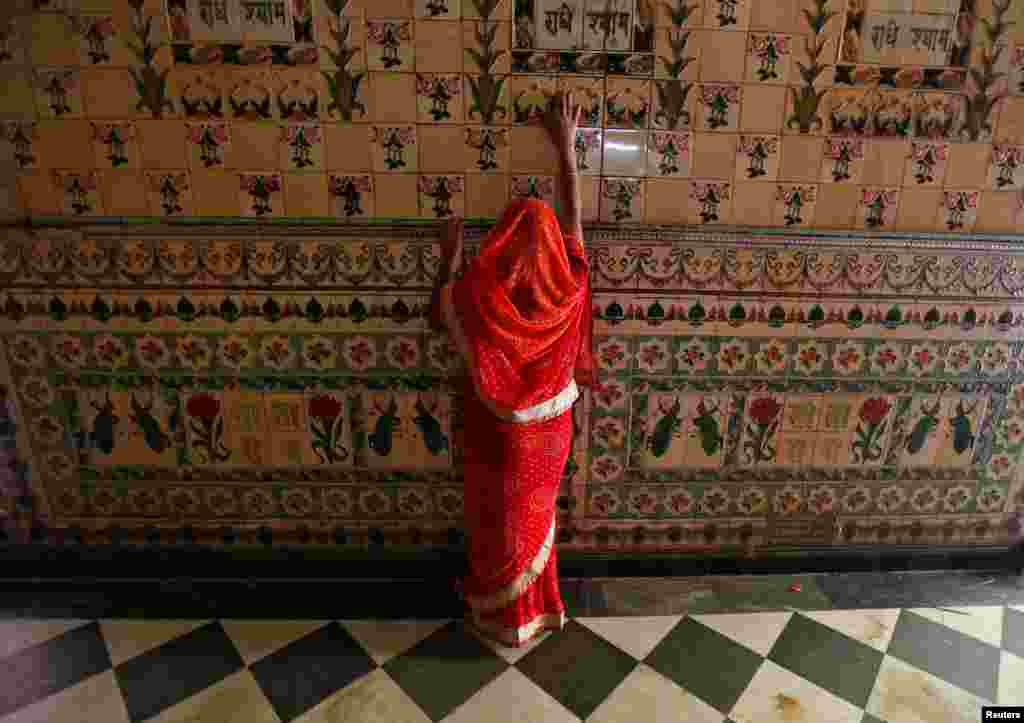 A woman prays as she touches the wall of a temple during Navratri festival in Kolkata, India.