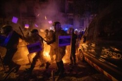 Policemen in riot gear move past a burning barricade during clashes with protestors in Barcelona, Spain, Oct. 15, 2019.