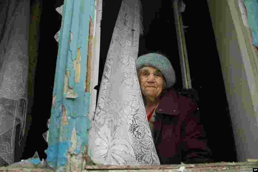 An elderly woman looks from her damaged apartment after artillery shook Donetsk, eastern Ukraine. Heavy shelling hit both government- and rebel-controlled areas of eastern Ukraine as fighting continued Friday.