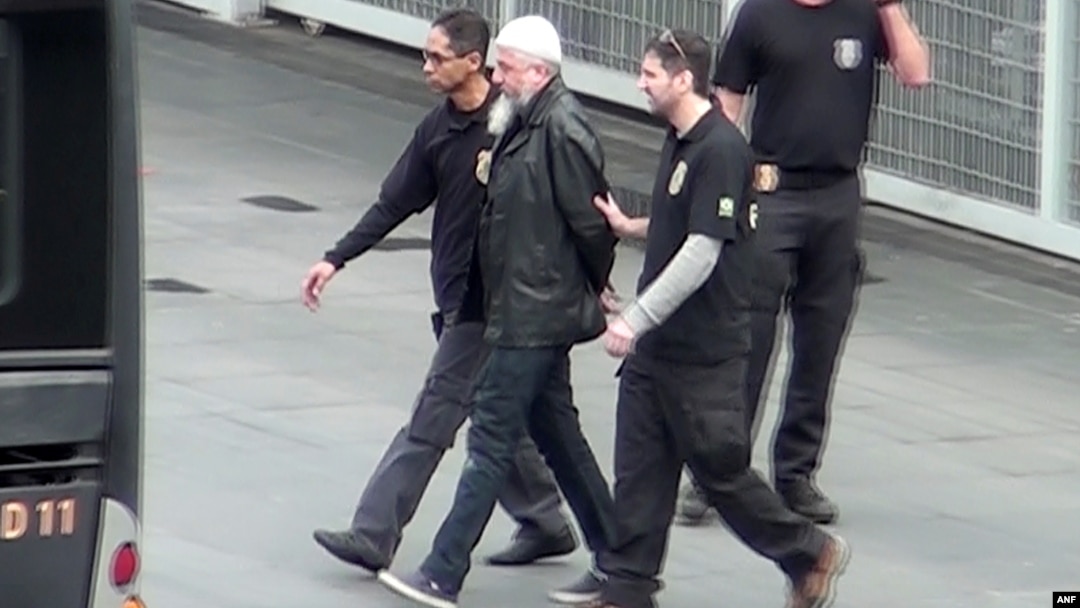 Brazilian Federal Police officers escort one of the 10 people they arrested on suspicions of belonging to a group supporting Islamic State and discussing terrorist acts during next month's Rio 2016 Olympic Games, at the Guarulhos airport in Sao Paulo, in 