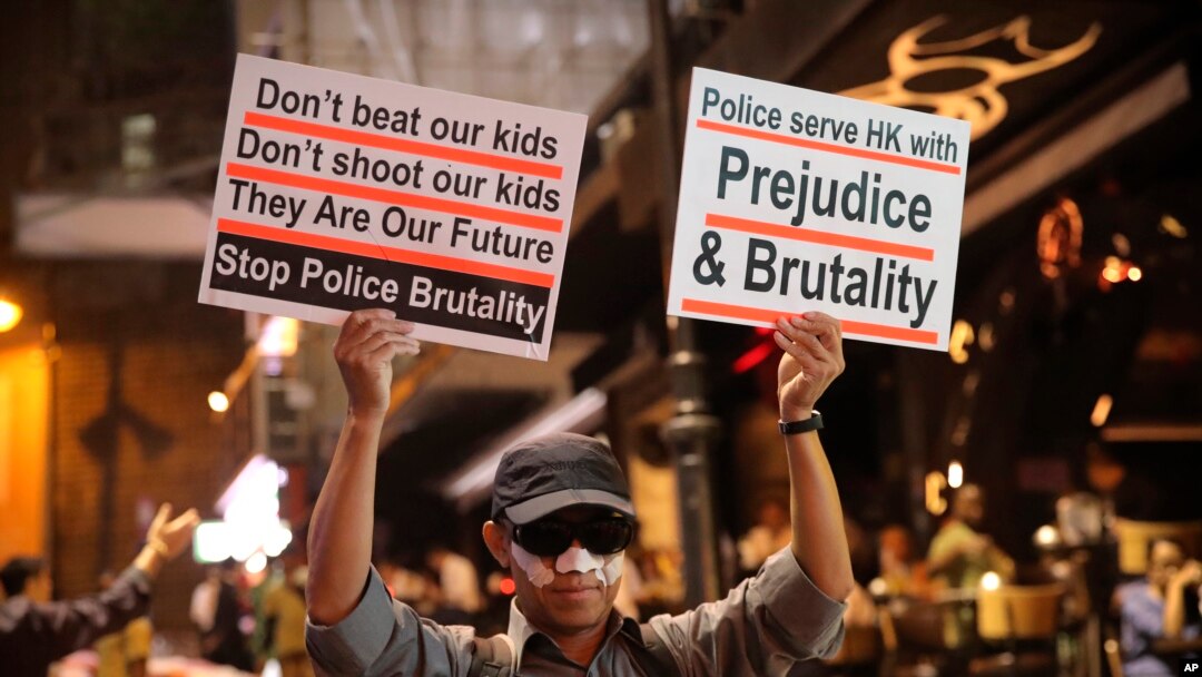 A man holds signs decrying police brutality in Hong Kong, Oct. 31, 2019. 