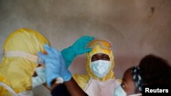 FILE - Healthcare workers adjust gear during a funeral of a person who is suspected of dying of Ebola in Beni, North Kivu Province of Democratic Republic of Congo, Dec. 9, 2018. 