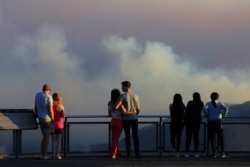 People watch as smoke from the Green Wattle Creek fire is seen from Echo Point lookout in Katoomba, as bushfires continue to blaze in New South Wales, Australia, Dec. 6, 2019.