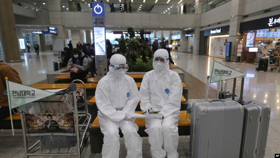 Chonnam National University staff wearing protective attire are on standby for special transportation for Chinese students studying at their university, at Incheon International Airport in Incheon, South Korea, Feb. 25, 2020.
