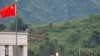 FILE - Myanmar government troops stand on a rooftop on the Myanmar side, near a Chinese flag from the Chinese border town of Nansan in southwestern China's Yunnan province, Sunday, Aug 30, 2009