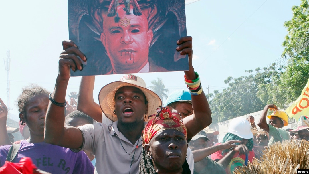 Demonstrator carries portrait depicting Prime Minister Laurent Lamothe as demon during anti-government protest, Port-au-Prince, Dec. 6, 2014.