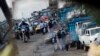 FILE - A reflection from the wing mirror of a car shows people ride motorcycles in Douala.