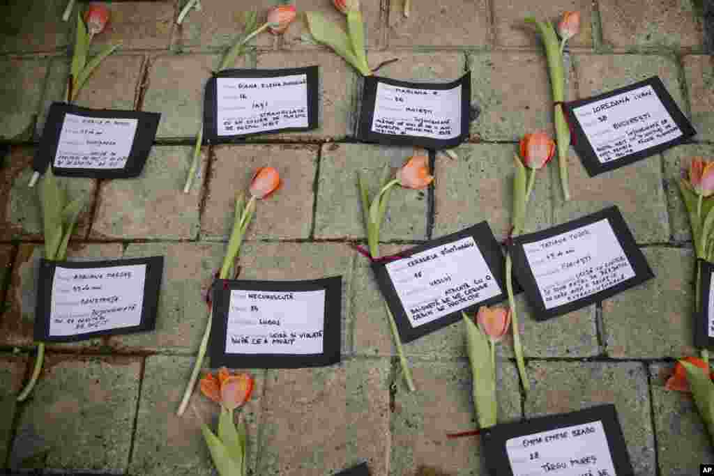 Flowers and cards with names and causes of death are placed on the ground during a performance to raise awareness for the plight of women killed by their partners, in Romania, marking International Women's Day, in Bucharest.