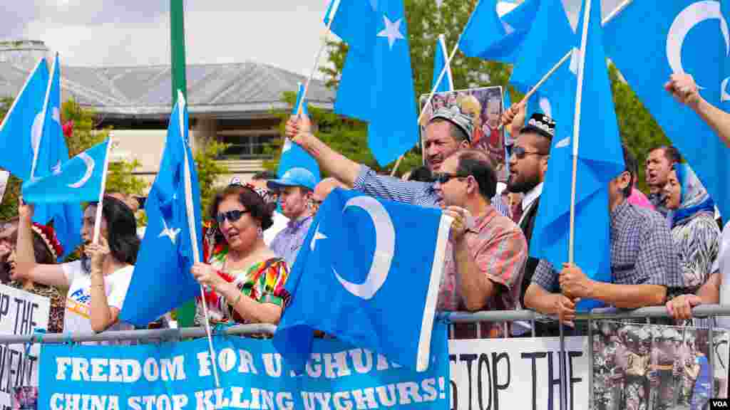 Uyg'urlar Sharqiy Turkiston bayroqlarini ko'tarib, Xitoy elchixonasi qarshisida bu davlatning uyg'urlarga qarshi siyosatini qoralab, namoyish qilmoqda, Vashington, 3-avgust, 2014-yil. Odil Ruzaliev surati