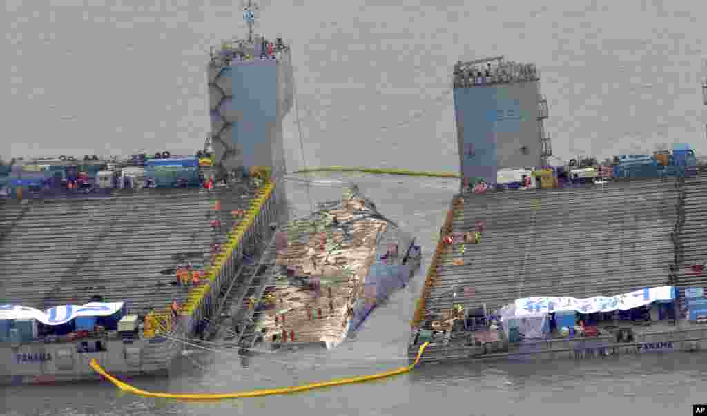 Workers prepare to lift the sunken Sewol ferry, center, in waters off Jindo, South Korea. The 6,800-ton ferry emerged from the water, nearly three years after it capsized and sank into violent seas off the country's southwestern coast.