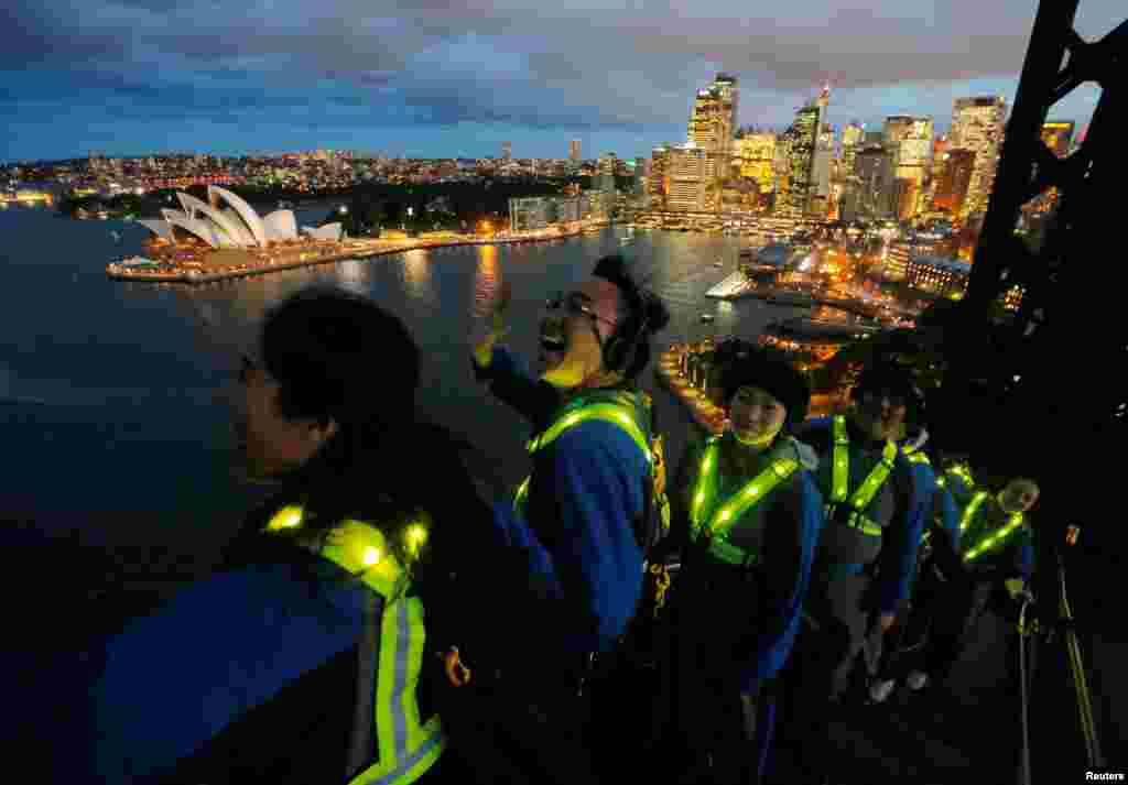 Participants wear glowing vests as they look out to the Sydney Opera House from the Sydney Harbour Bridge in Australia during a press preview of the Vivid Climb Mandarin for Chinese-language tours of the Sydney icon.