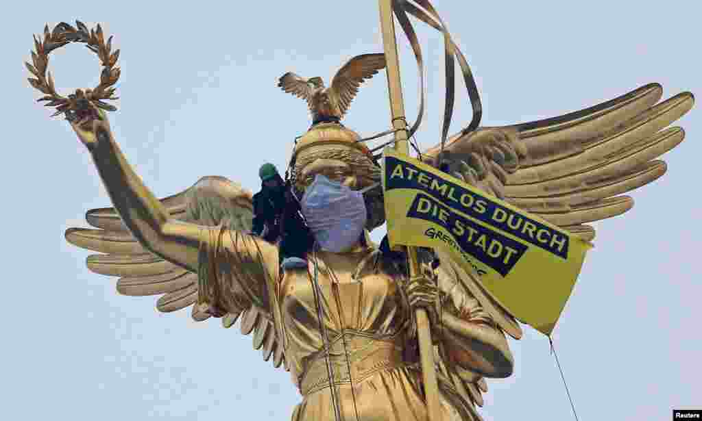 Greenpeace activists climb the Golden Victoria monument and install a banner "Breathless through the city" to protest against air pollution in Berlin, Germany.