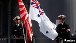 FILE - Crew members from the Japanese Maritime Self-Defense force ship Umigiri stand on deck between Japan's Self-Defense Force flag alongside an Australian flag before joint exercises at Garden Island Naval Base in Sydney, April 19, 2016. 