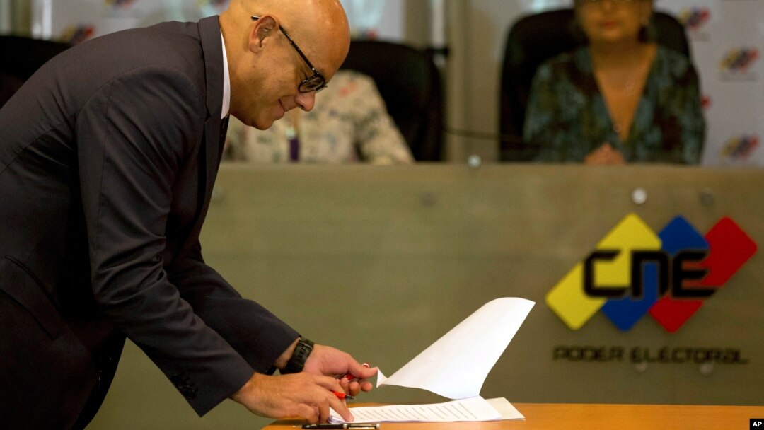 Communications Minister Jorge Rodriguez signs an agreement made with several opposition parties to delay presidential elections at the Venezuelan National Electoral Council in Caracas, Venezuela, March 1, 2018. 