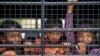 Cambodian migrants look through grills of a truck as they wait to cross the Thai-Cambodia border at Aranyaprathet in Sa Kaew, June 15, 2014. A high percentage of migrants have at some point experienced exploitation and human trafficking, official figures show.