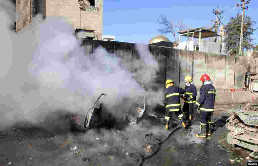 Firefighters hose down a destroyed vehicle at the site of a suicide bomb attack in Kirkuk, Iraq, Feb. 3, 2013.