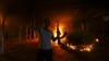 A protester reacts as the U.S. Consulate in Benghazi is seen in flames during a protest by an armed group said to have been protesting a film being produced in the United States September 11, 2012. 