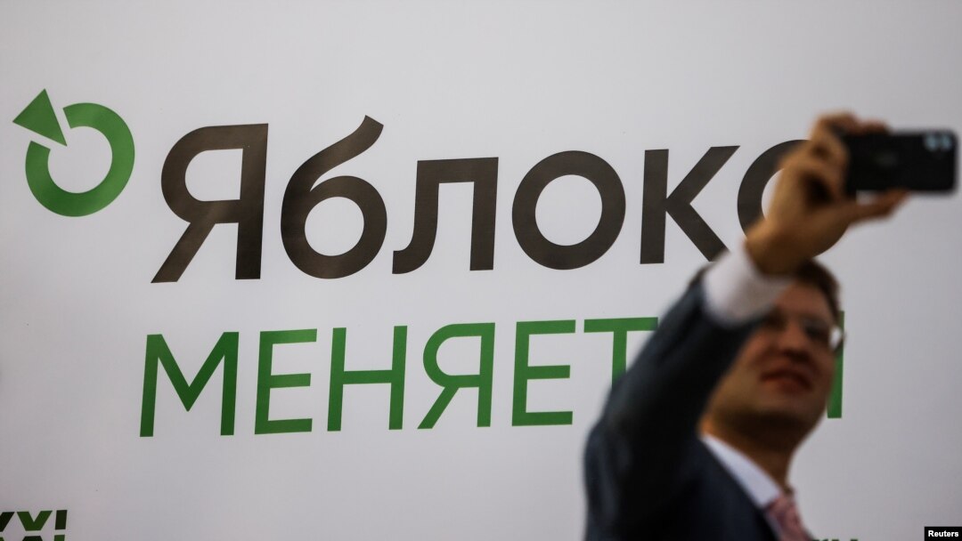 A participant takes a selfie in front of a banner during a congress of the political party Yabloko in Moscow, Russia, April 3, 2021. A banner reads: "Yabloko is changing." 