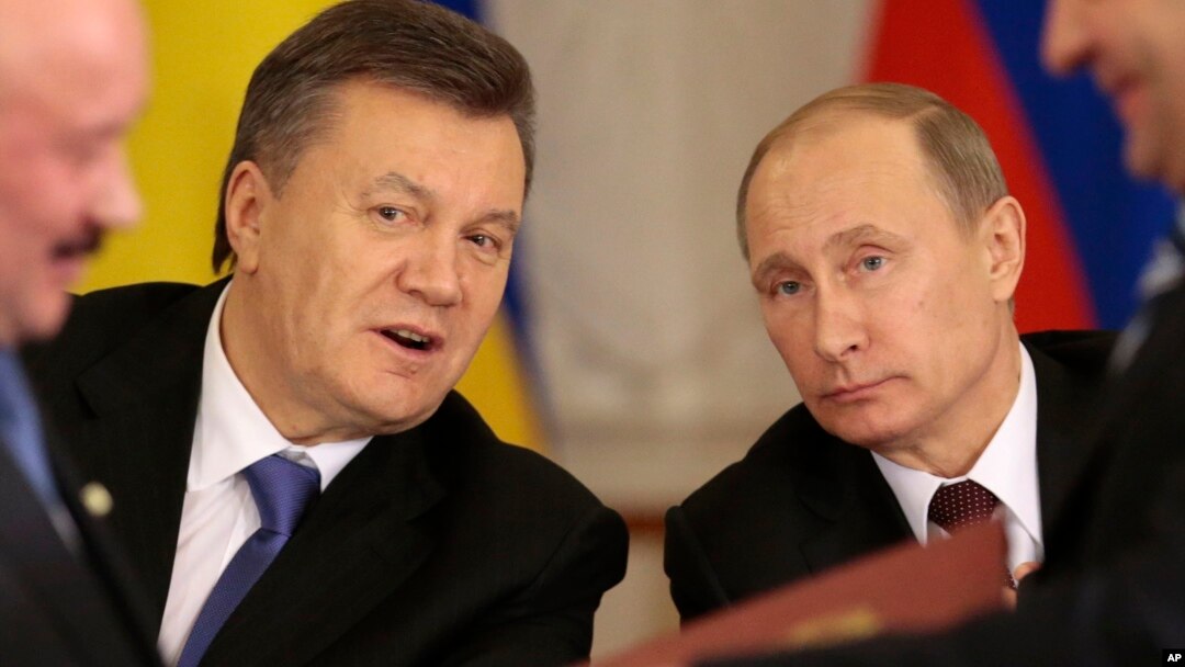 Russian President Vladimir Putin, right, and his Ukrainian counterpart Viktor Yanukovych, left, react after signing an agreement in Moscow, Dec. 17, 2013.