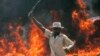 A supporter of the Orange Democratic Party hold up a machete in front of a burning baricade during riots in the Kibera slum in Nairobi, (File photo).