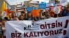 FILE - Demonstrators hold signs in front of the High Education Board during a protest against the suspension of academics from universities following a post-coup emergency decree, in Ankara, Turkey, Sept. 22, 2016. The sign in the foreground reads "Let the emergency decrees go. We are remaining."