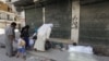 Syrian citizens look at dead bodies on a roadside in front of al-Shifa hospital, al-Shaar neighborhood, Aleppo city, Sept. 24, 2012.