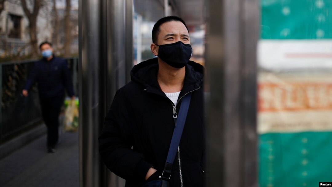A man wearing a face mask looks at a board at a bus stop, as the country is hit by an outbreak of the new coronavirus, in Beijing, China January 27, 2020.