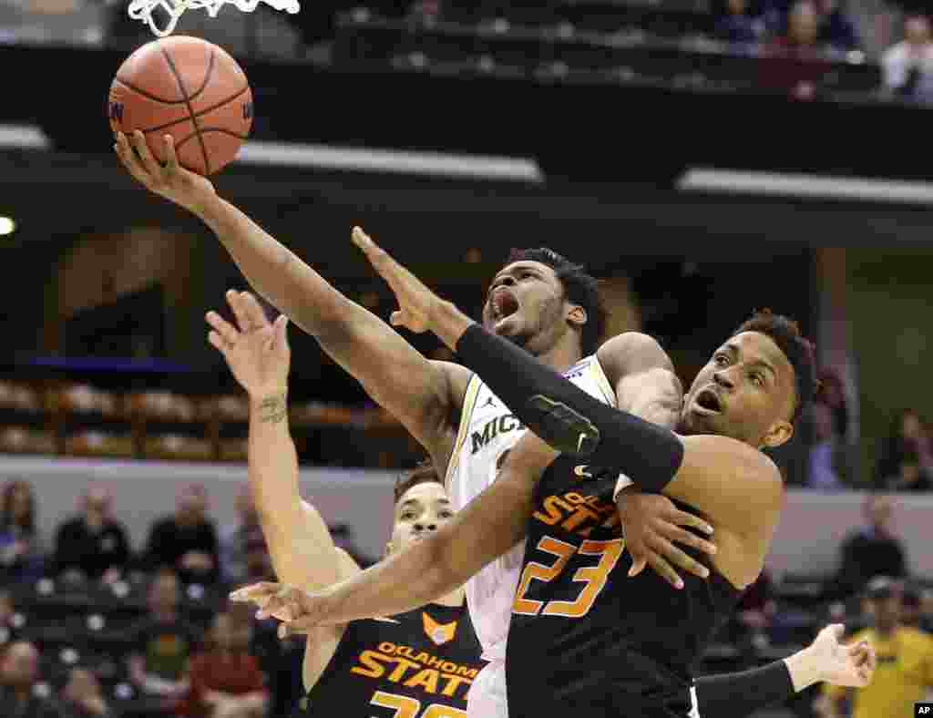 University of Michigan guard Derrick Walton Jr. (10) is fouled as he shoots by Oklahoma State University forward Leyton Hammonds (23) during a first-round game in the men's NCAA college basketball tournament in Indianapolis, Indiana.