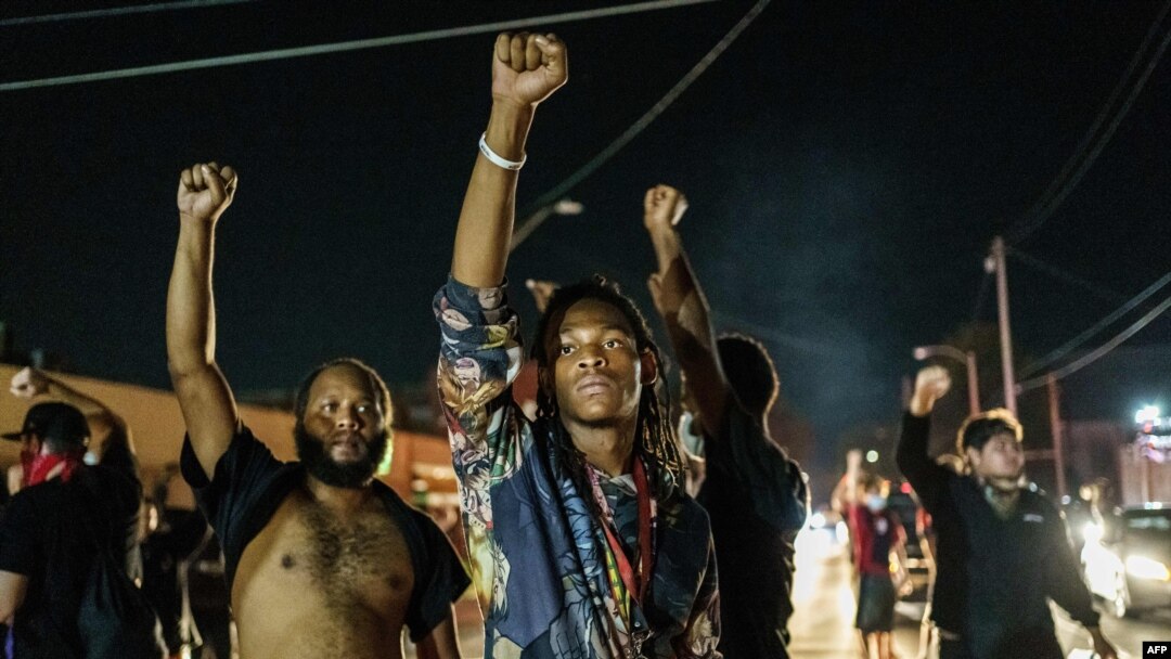 Protesters raise their fists during a demonstration against the shooting of Jacob Blake in Kenosha, Wis., on Aug. 26, 2020.